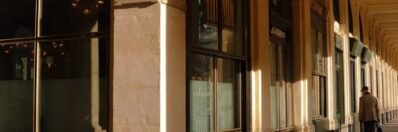 Sunlit corridor of Paris' Palais Royal highlighting classic architecture.